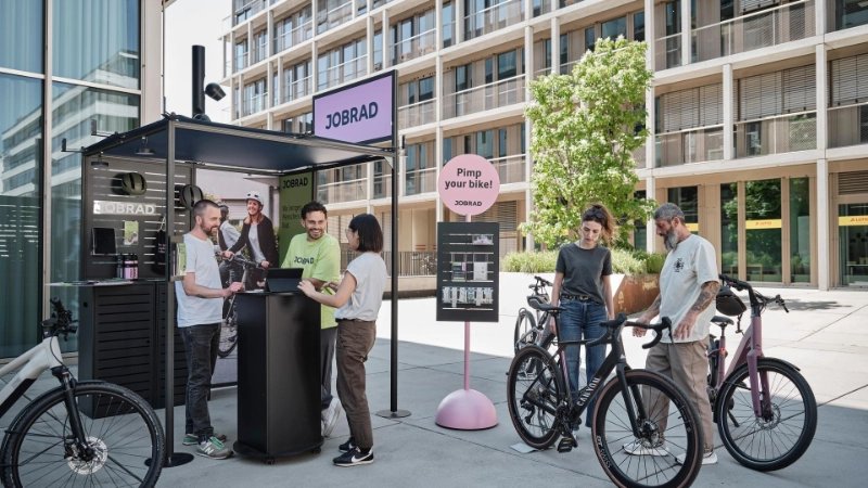 Beratungssituation am JobRad-Stand. Zentral ein Sticker-Aufsteller mit Schild "Pimp your Bike"